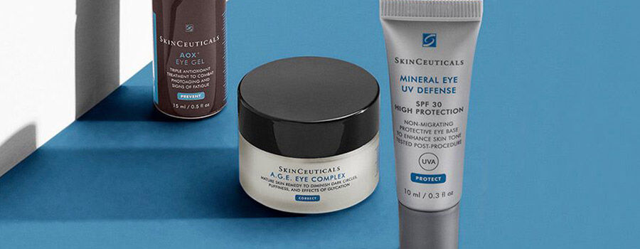 Skincare products from SkinCeuticals: AOX Eye Gel, A.G.E Eye Complex, and Mineral Eye UV Defense on a blue background.