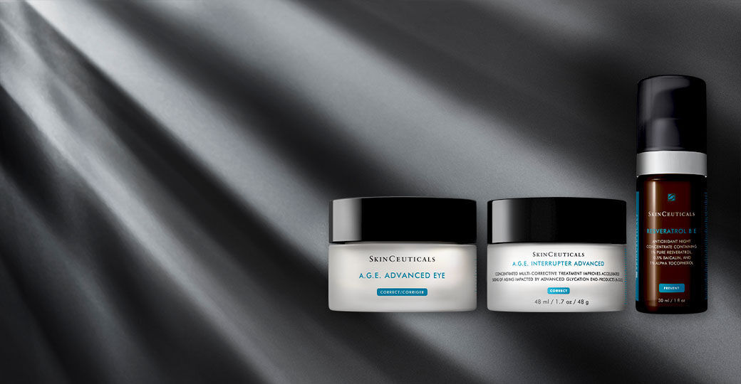 A collection of Skinceuticals skincare products displayed on a sleek, textured surface, featuring two jars labeled "A.G.E. Advanced Eye" and "A.G.E. Interrupter Advanced," along with a small serum bottle. Soft light illuminates the scene, creating a sophisticated ambiance.