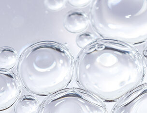 Close-up of translucent water bubbles on a reflective surface, creating a soft, shimmering effect.