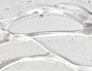 Close-up of clear gel with a smooth texture, layered over a light-colored, textured surface.