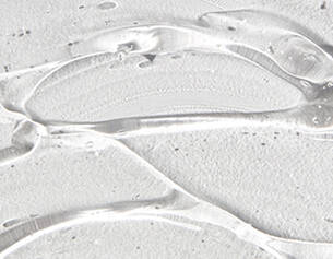 Close-up of clear gel with a smooth texture, layered over a light-colored, textured surface.