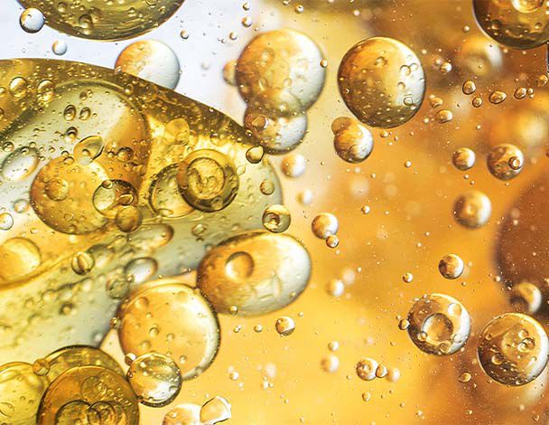 Abstract close-up of bubbles and droplets in shimmering golden liquid, creating a dynamic and vibrant texture.