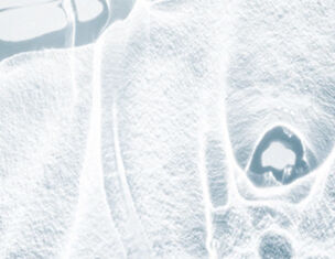 Abstract close-up of a textured, light-colored surface with undulating lines and shapes, creating a fluid appearance.