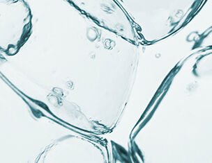 Close-up of shimmering ice cubes submerged in clear water with bubbles rising around them.