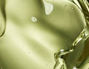 Close-up of olive oil, showcasing its smooth, golden-green texture and light refractions.