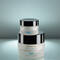 Two jars of SkinCeuticals skincare products are stacked on a reflective surface. The top jar is labeled "A.G.E. Eye Complex" and the bottom jar is labeled "A.G.E. Interrupter." The background is softly lit, emphasizing the jars' elegant design.