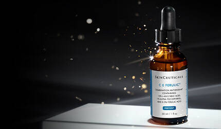 A dropper bottle of skincare serum with a dark background and soft lighting, featuring particles that create a glowing effect around it.
