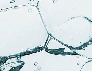 Close-up of bubbles and ice cubes submerged in clear water, creating an abstract, refreshing visual effect.