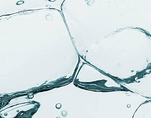 Close-up of bubbles and ice cubes submerged in clear water, creating an abstract, refreshing visual effect.