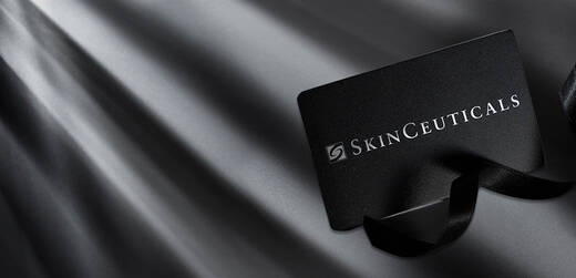 A sleek black gift card for SkinCeuticals placed on a dark, textured background with soft light creating a dramatic effect.