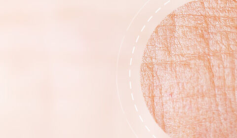 Abstract texture of soft, peach-colored fabric with a faint circular pattern and light lines.