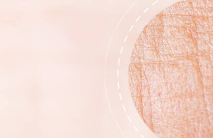Abstract texture of soft, peach-colored fabric with a faint circular pattern and light lines.