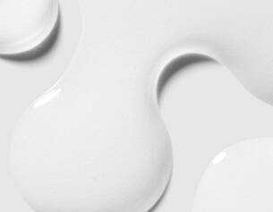 Abstract close-up of glossy white paint blobs on a light background, creating a smooth, fluid texture.