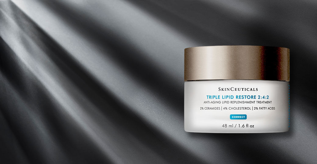 A jar of SkinCeuticals Triple Lipid Restore 2:4:2 anti-aging cream on a dark, textured background with subtle rays of light.