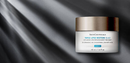 A jar of SkinCeuticals Triple Lipid Restore 2:4:2 anti-aging cream on a dark, textured background with subtle rays of light.