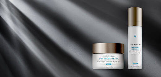 Two skincare products from SkinCeuticals are displayed against a dark, light-ray background. The first is a jar of Triple Lipid Restore 2:4:2, and the second is a bottle of Trifarotene 0.25% Emollient Treatment.