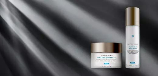 Two skincare products from SkinCeuticals are displayed against a dark, light-ray background. The first is a jar of Triple Lipid Restore 2:4:2, and the second is a bottle of Trifarotene 0.25% Emollient Treatment.