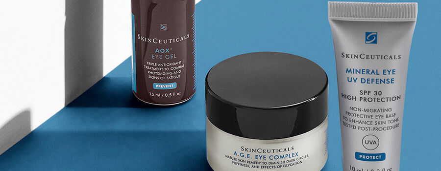 Three skincare products from SkinCeuticals displayed against a blue background: AOX Eye Gel, A.G.E. Eye Complex, and Mineral Eye UV Defense SPF 30.
