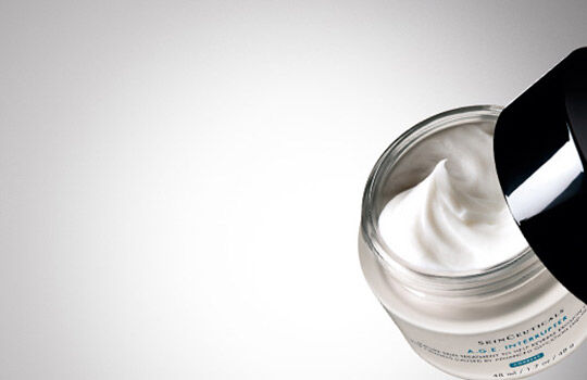 A close-up of an open jar of skincare cream against a gradient background, showcasing the creamy texture inside.