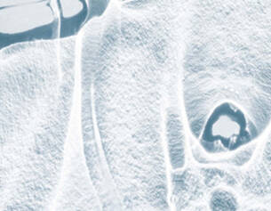 Abstract close-up of a textured icy surface, showcasing patterns and reflections in a pale blue hue.
