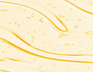 A close-up of a smooth, glossy yellow liquid with small bubbles and gentle, flowing waves in its texture.