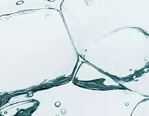 Close-up of ice cubes submerged in clear water, with bubbles rising and creating a refreshing visual effect.