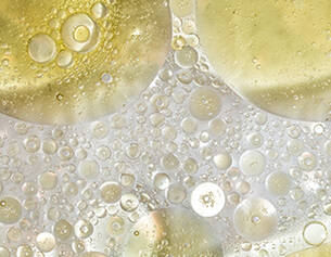 Close-up of oil and water bubbles in varying sizes, creating an abstract pattern with golden hues.