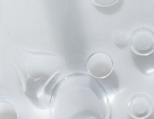 Close-up of clear liquid with various sizes of bubbles reflecting light, creating a textured and glossy surface.