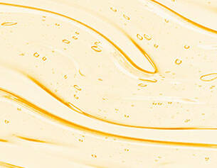 A close-up of yellow liquid flowing with bubbles, creating smooth, wavy patterns.