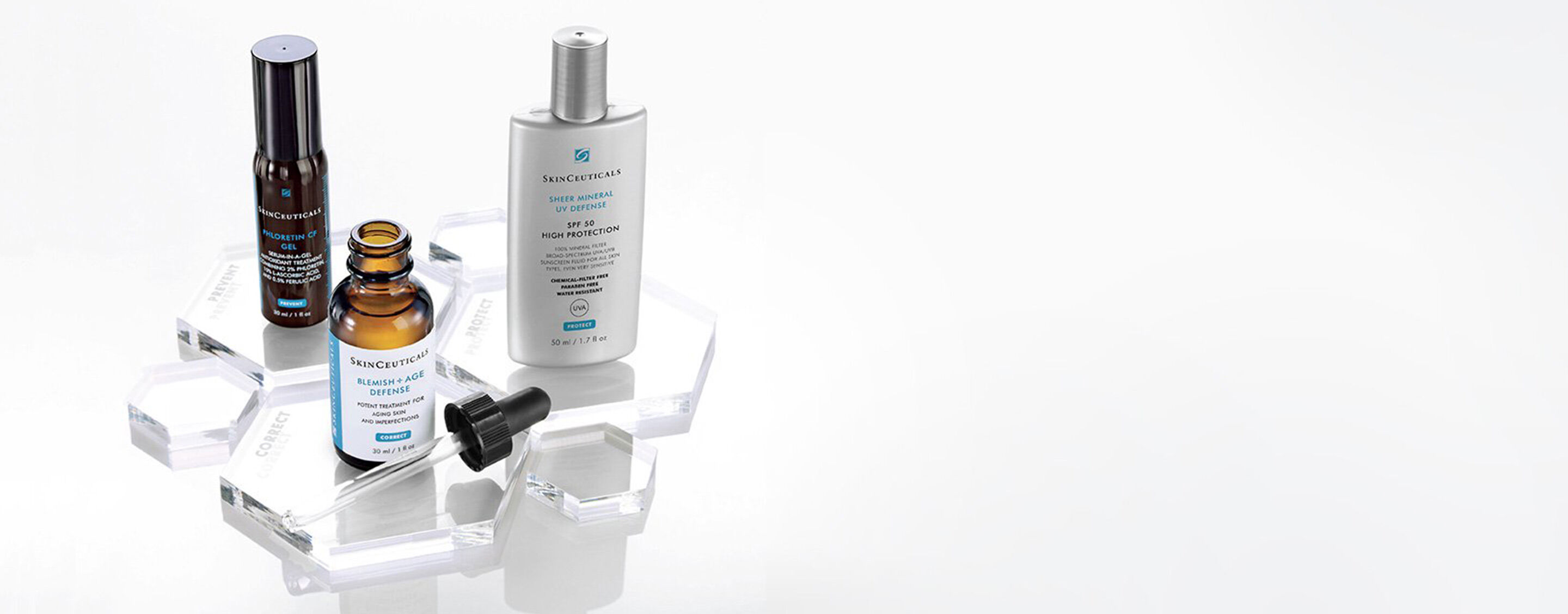 A minimalist display of skincare products from SkinCeuticals, including serums and a moisturiser on a clear surface.