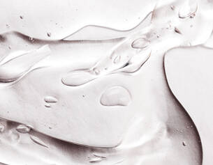 Close-up of translucent gel with droplets and smooth, flowing textures on a light background.