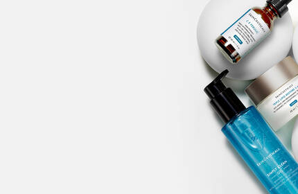 A collection of skincare products, including serums, moisturizers, and sunscreen, arranged on a light background.