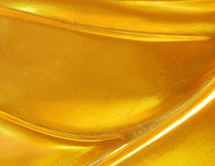 Close-up of a smooth, golden surface with flowing curves, reflecting light and emphasizing its luminous quality.