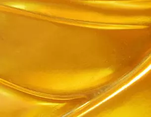 Close-up of a smooth, golden surface with flowing curves, reflecting light and emphasizing its luminous quality.