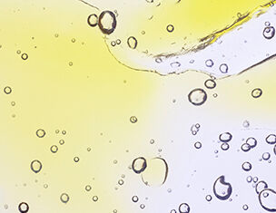 Close-up of bubbles in a vibrant yellow and clear liquid, creating an abstract and dynamic visual effect.
