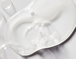 Clear gel or fluid spread on a white surface, showcasing its smooth texture and reflective quality.