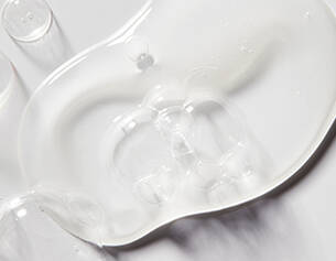 Clear gel or fluid spread on a white surface, showcasing its smooth texture and reflective quality.