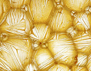 Magnified view of crystalline structures with a golden hue, showcasing intricate patterns and textures.