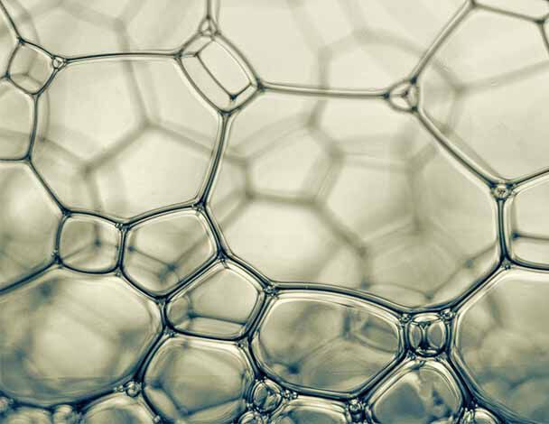 Close-up of translucent soap bubbles, showcasing intricate hexagonal shapes and delicate structures within.