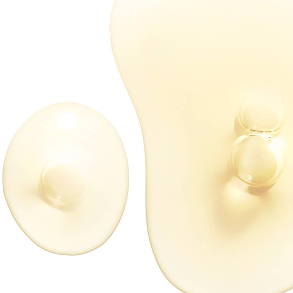 Two blobs of translucent, pale yellow liquid, one larger and irregularly shaped, the other smaller and round.