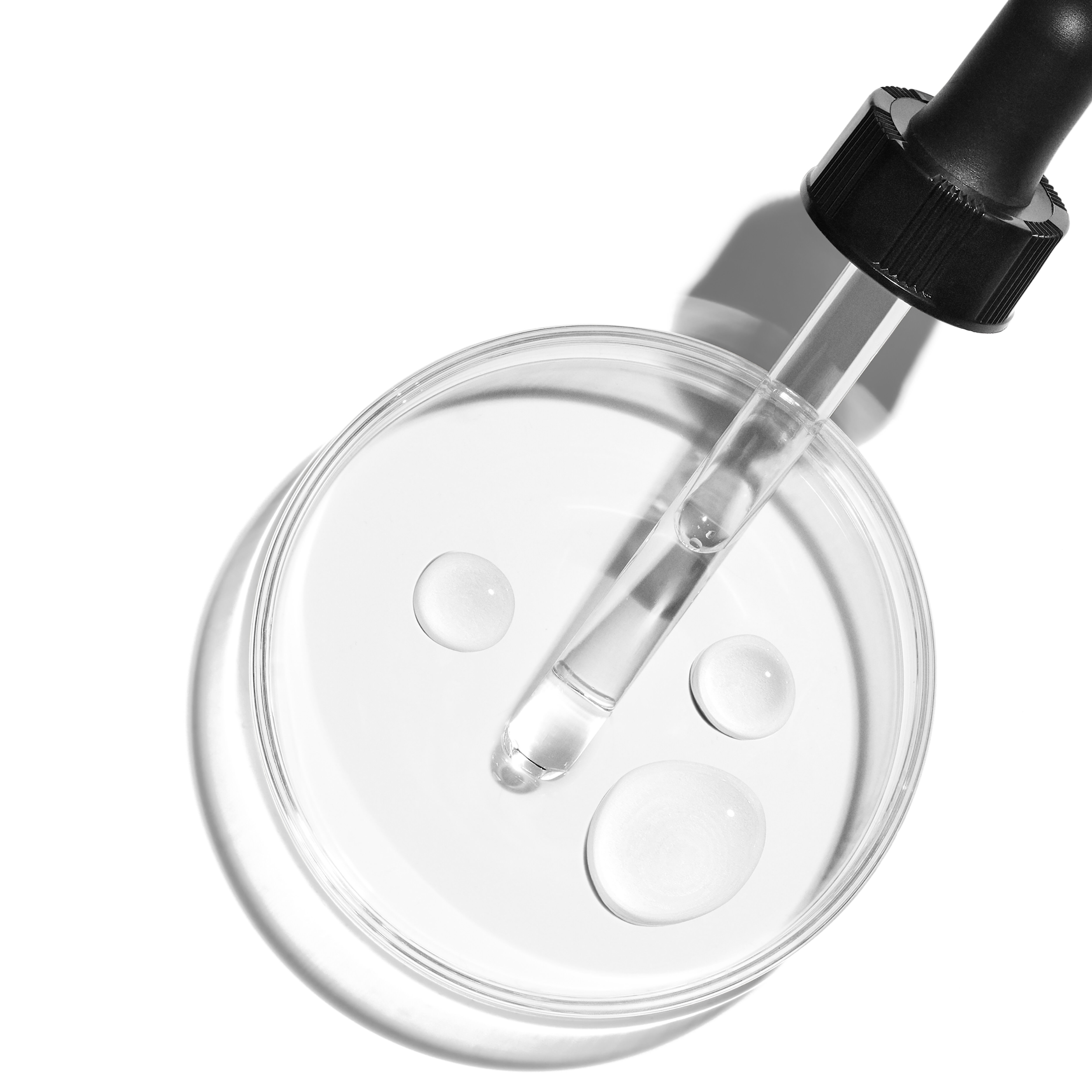A woman dispensing a golden vitamin c serum onto her radiant cheek