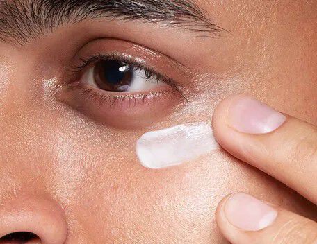 Man applying an eye cream under his eye