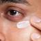 Man applying an eye cream under his eye