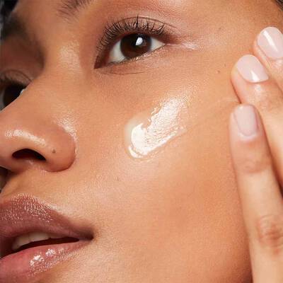 Woman applying glistening cream formula to her cheek