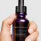 Hand holding H.A. Intensifer serum against a grey background