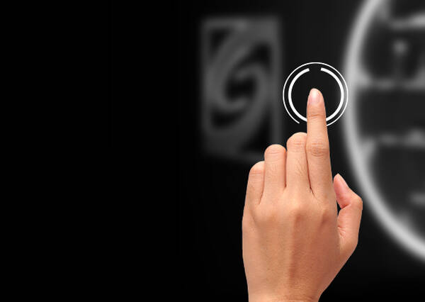 A hand is poised to touch a circular interface on a dark background, with a display of shelves visible in the blurred background.