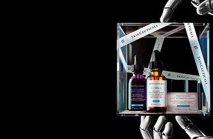 A display featuring various skincare products, including serums and treatments, arranged on a reflective surface against a dark background.