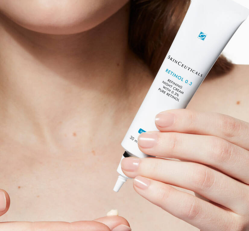 A person applying SkinCeuticals Retinol 0.3 Refining Night Cream with 0.3% pure retinol from a white tube.