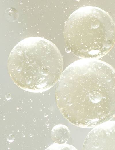 Close-up image of Niacinamide skincare ingredient. Light, bubbly liquid with a soft champagne color.